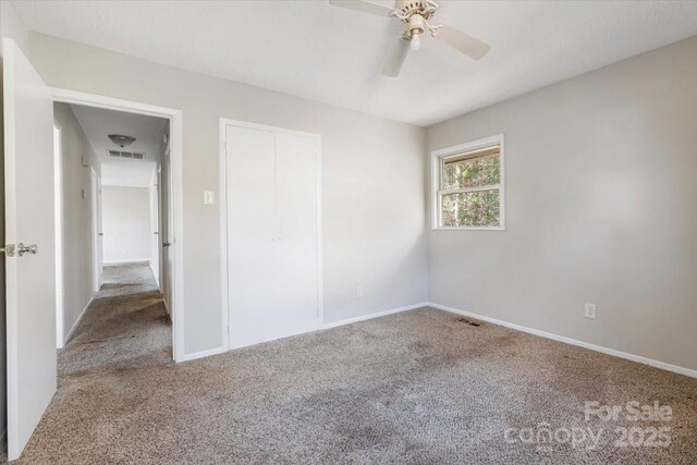 carpeted empty room with a ceiling fan, baseboards, and visible vents