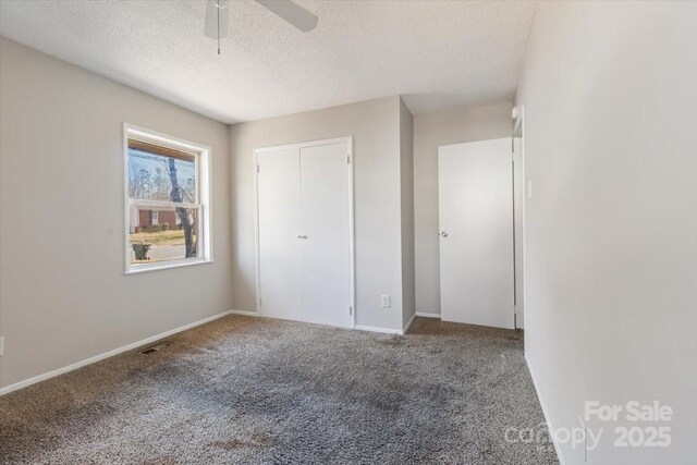 unfurnished bedroom featuring visible vents, carpet, and a textured ceiling