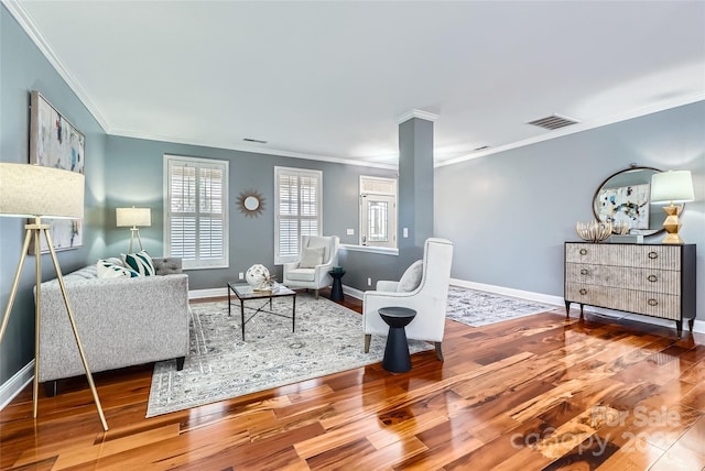 living area with visible vents, baseboards, wood finished floors, and ornamental molding