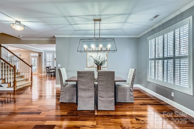 dining room featuring wood finished floors, visible vents, baseboards, stairs, and crown molding