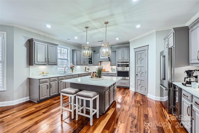 kitchen featuring gray cabinets, appliances with stainless steel finishes, a center island, and a sink