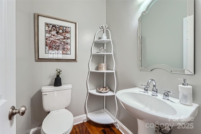 bathroom featuring wood finished floors, toilet, and a sink