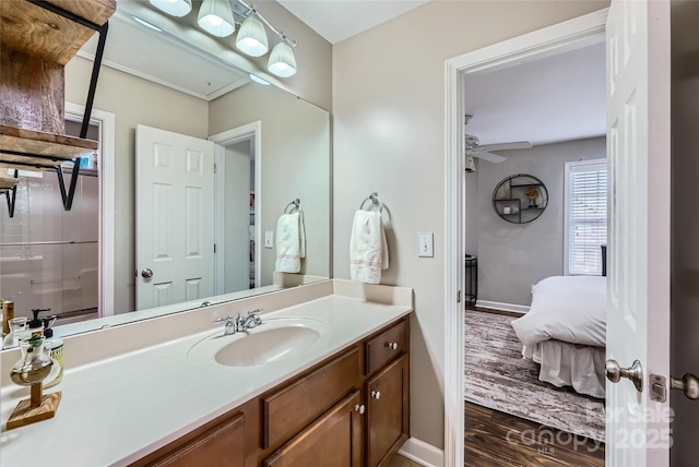 ensuite bathroom featuring vanity, wood finished floors, a ceiling fan, baseboards, and ensuite bath