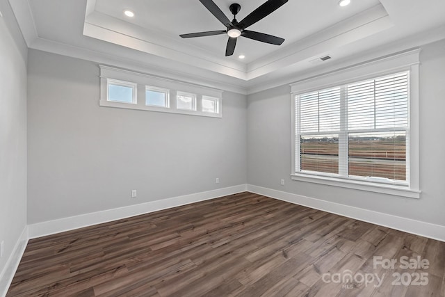 spare room with dark wood finished floors, a raised ceiling, and visible vents