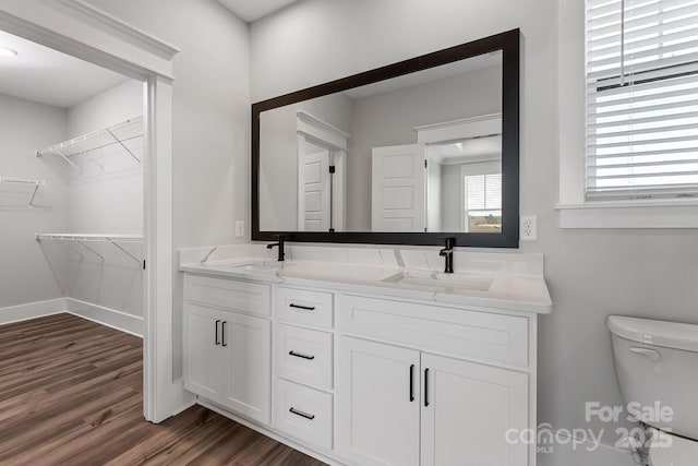 full bathroom featuring double vanity, toilet, a sink, and wood finished floors