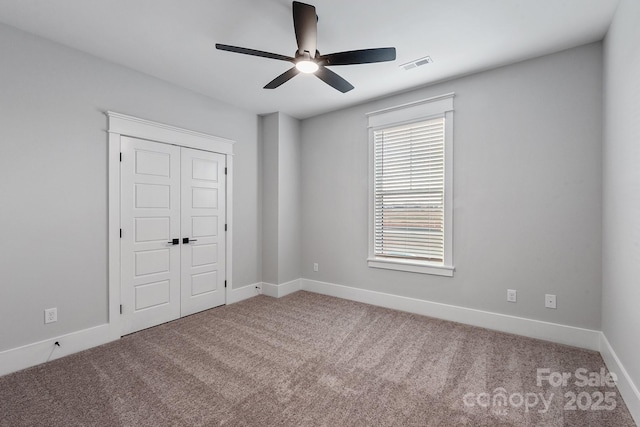 unfurnished bedroom featuring a ceiling fan, visible vents, baseboards, a closet, and carpet