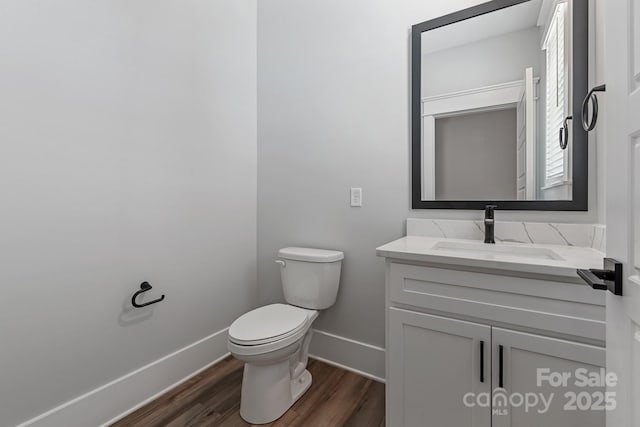 bathroom with toilet, baseboards, wood finished floors, and vanity