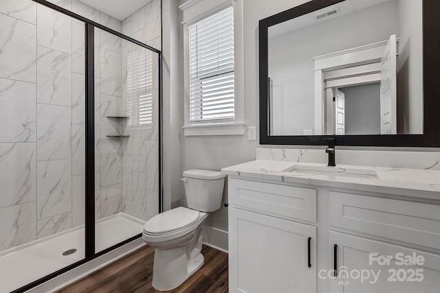 full bathroom with toilet, wood finished floors, vanity, visible vents, and a stall shower