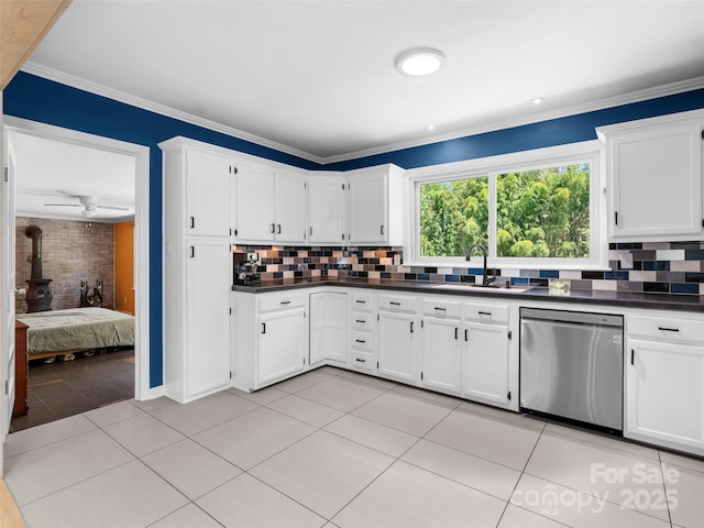 kitchen with light tile patterned floors, dark countertops, a wood stove, stainless steel dishwasher, and a sink
