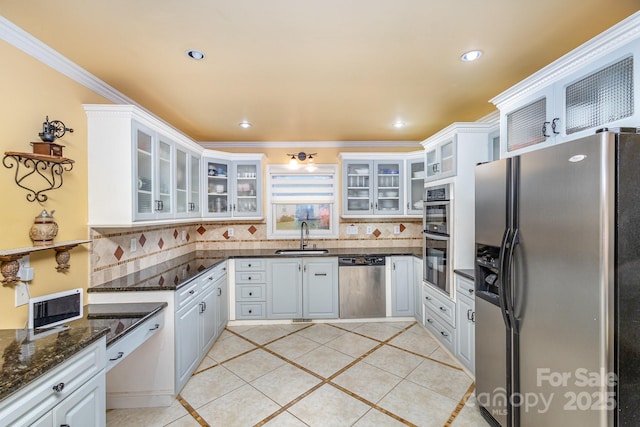 kitchen featuring decorative backsplash, stainless steel appliances, crown molding, and a sink