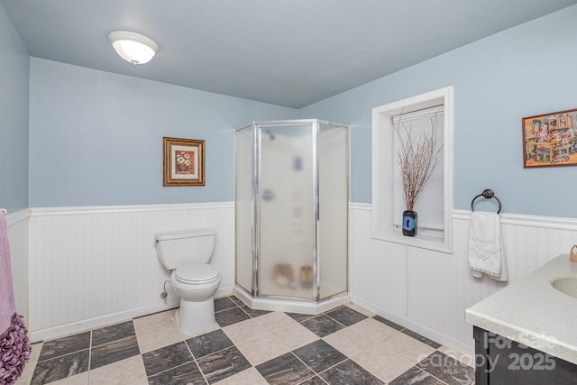 full bath with wainscoting, vanity, toilet, and a shower stall