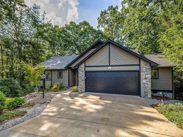 view of front of property featuring stone siding, an attached garage, and concrete driveway