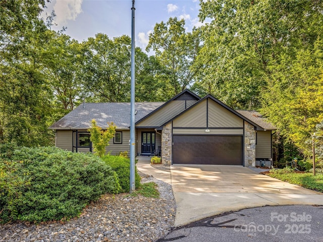 view of front of property with stone siding, an attached garage, and concrete driveway