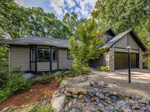 view of front of home featuring an attached garage, stone siding, and concrete driveway