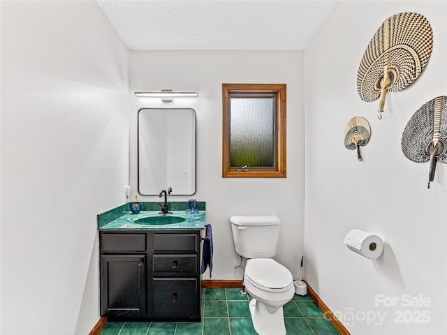 bathroom with toilet, vanity, a textured ceiling, baseboards, and tile patterned floors