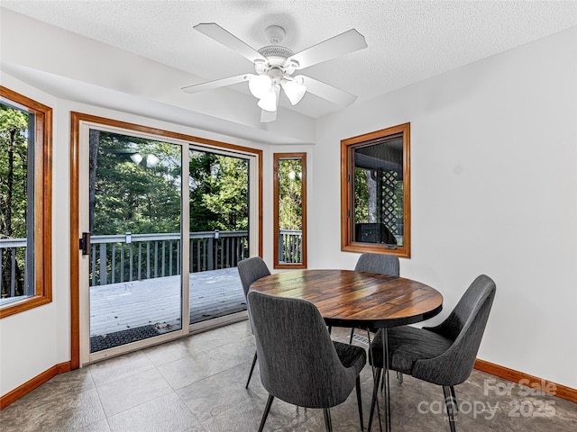 dining space with a textured ceiling, a ceiling fan, and baseboards