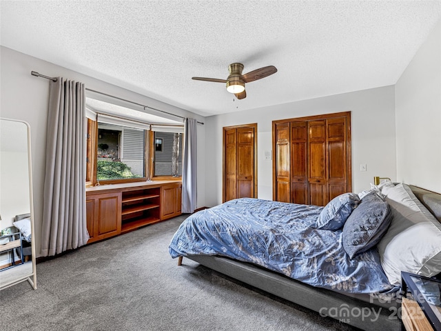 carpeted bedroom featuring ceiling fan, a textured ceiling, and multiple closets