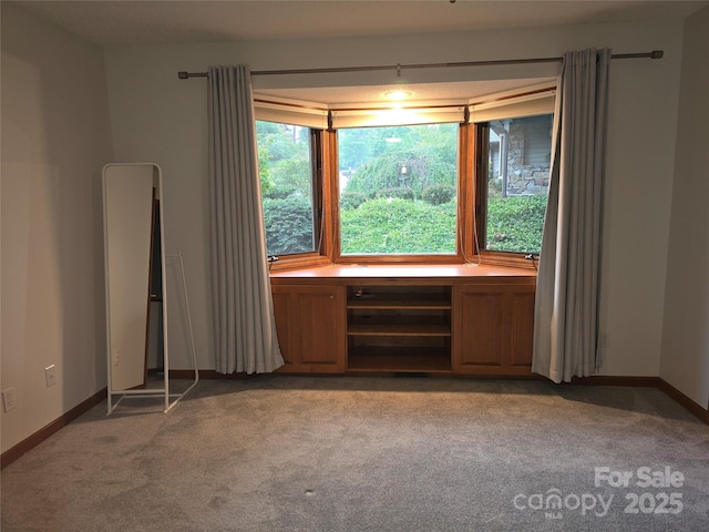 empty room featuring light carpet and baseboards