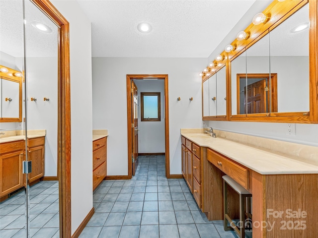 bathroom featuring tile patterned flooring, baseboards, vanity, and a textured ceiling