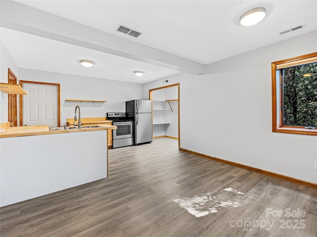 kitchen featuring appliances with stainless steel finishes, visible vents, a sink, and open shelves