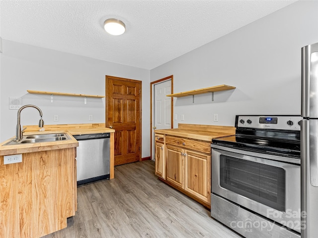 kitchen featuring appliances with stainless steel finishes, butcher block counters, a sink, and open shelves