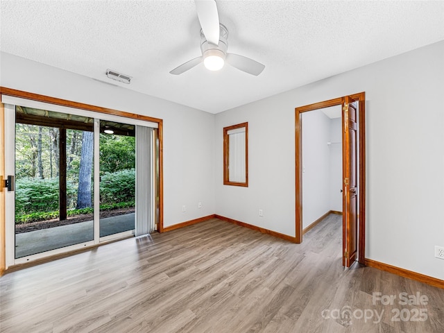 unfurnished room with baseboards, visible vents, a textured ceiling, and light wood finished floors