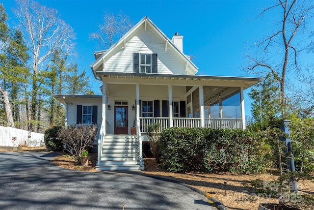 view of front of property with a porch, a chimney, fence, and stairway