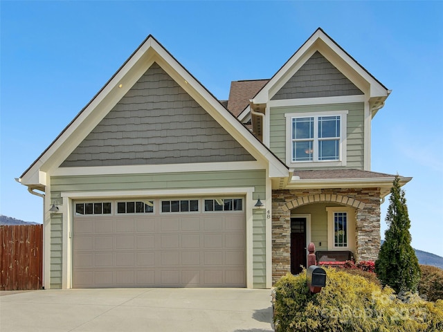 craftsman house featuring concrete driveway, stone siding, roof with shingles, an attached garage, and fence