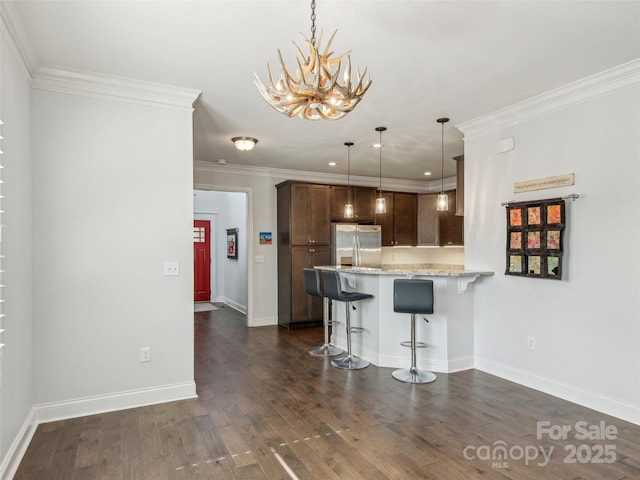 kitchen with a peninsula, a breakfast bar, dark wood-style flooring, stainless steel refrigerator with ice dispenser, and crown molding