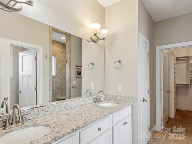 full bath with double vanity, a stall shower, baseboards, and a sink