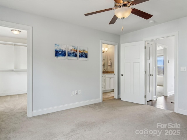 unfurnished bedroom featuring carpet, a closet, a spacious closet, ensuite bath, and baseboards