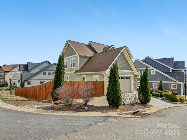 view of front of house with an attached garage, fence, and a residential view