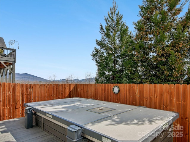 wooden deck with a covered hot tub and fence