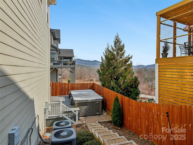 view of yard featuring a mountain view, a hot tub, and fence