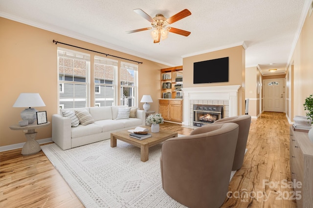 living room featuring a textured ceiling, light wood finished floors, and a tile fireplace