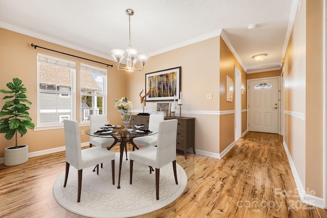 dining space featuring a chandelier, baseboards, light wood-style floors, and ornamental molding