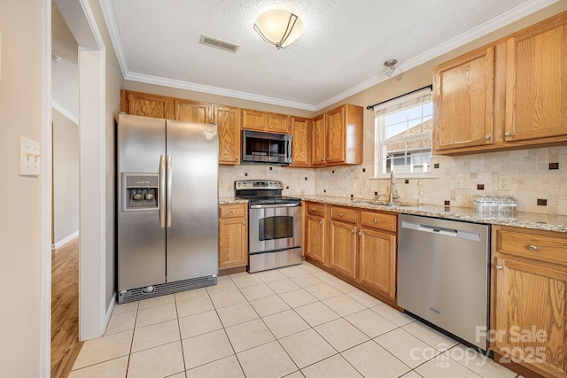 kitchen with light stone countertops, visible vents, a sink, stainless steel appliances, and backsplash