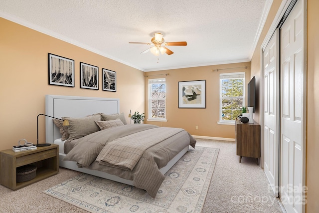 carpeted bedroom with baseboards, ceiling fan, ornamental molding, a closet, and a textured ceiling