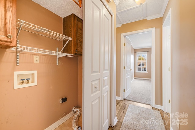 laundry room with washer hookup, ornamental molding, a textured ceiling, cabinet space, and baseboards