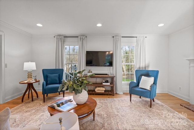 sitting room featuring crown molding, baseboards, wood finished floors, and a healthy amount of sunlight