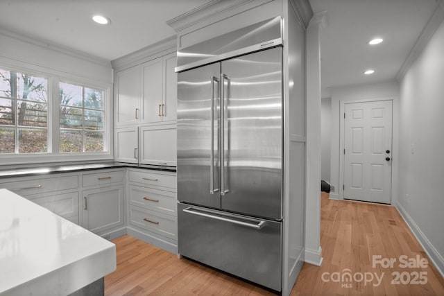 kitchen with crown molding, light wood finished floors, recessed lighting, and stainless steel built in fridge