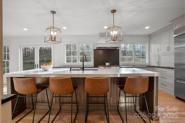 kitchen with light wood finished floors, tasteful backsplash, a sink, stainless steel built in refrigerator, and a wealth of natural light