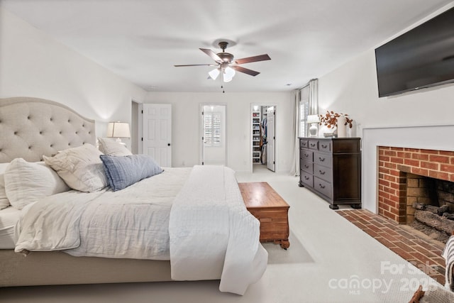 bedroom with a closet, a brick fireplace, ceiling fan, and a spacious closet