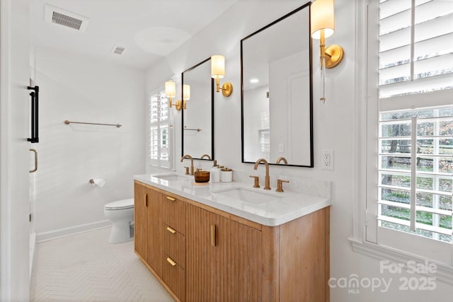 bathroom with visible vents, a sink, toilet, and double vanity