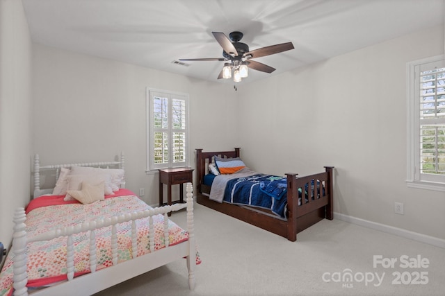 carpeted bedroom featuring a ceiling fan, visible vents, and baseboards