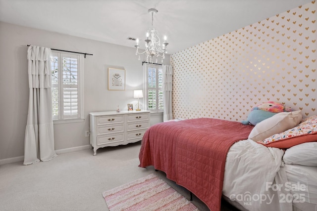 bedroom with light colored carpet, an inviting chandelier, an accent wall, baseboards, and wallpapered walls