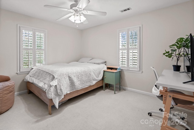 carpeted bedroom featuring visible vents, baseboards, and multiple windows