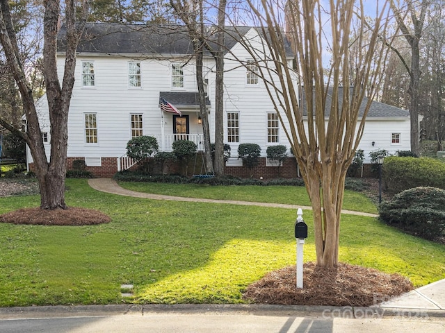 colonial house featuring crawl space, a shingled roof, and a front yard