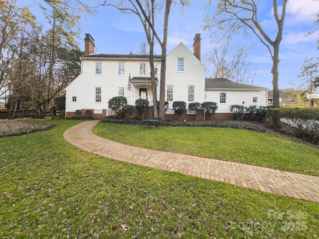 rear view of house with a chimney and a lawn