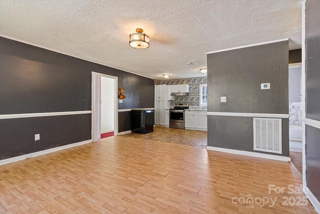 unfurnished living room featuring visible vents, a textured ceiling, and light wood-style floors